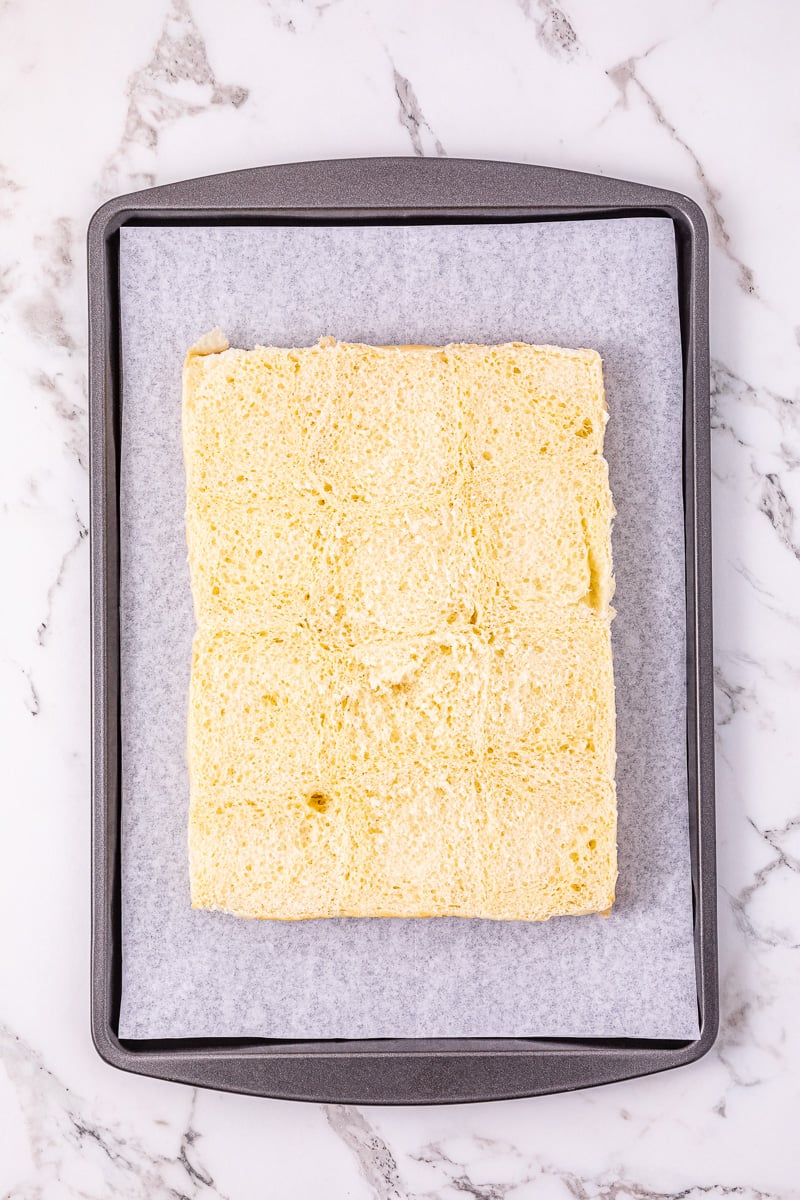 Bottom half of sliders placed on parchment lined baking sheet.