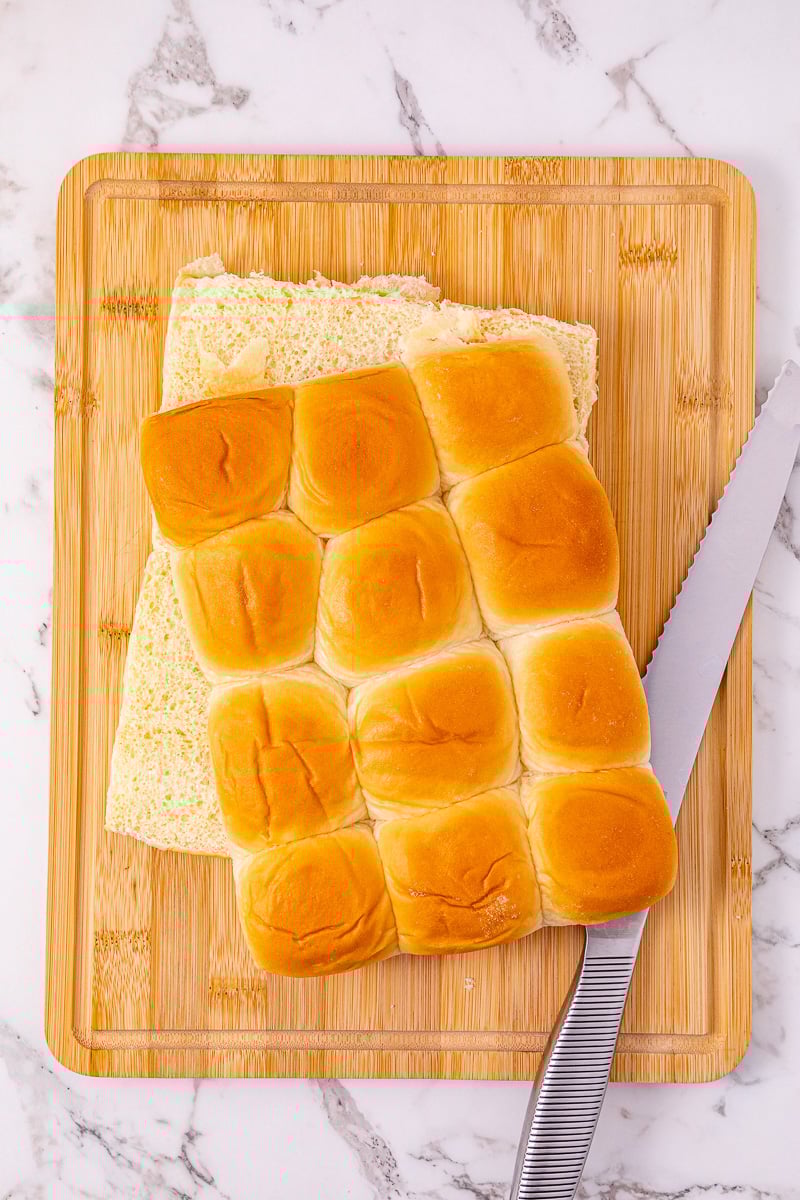 Sliders sliced in half on wooden board.