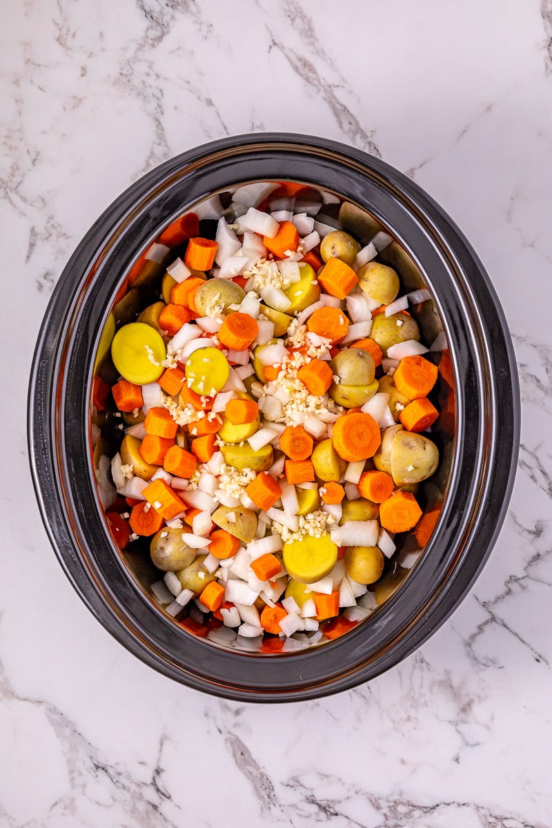 Carrots, potoates and onions are added to the crockpot.