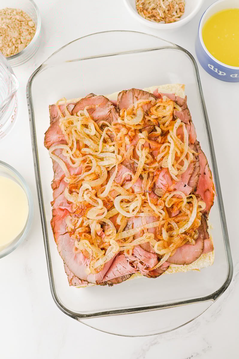 Onion mixture is added to the top of the roat beef on slider buns.