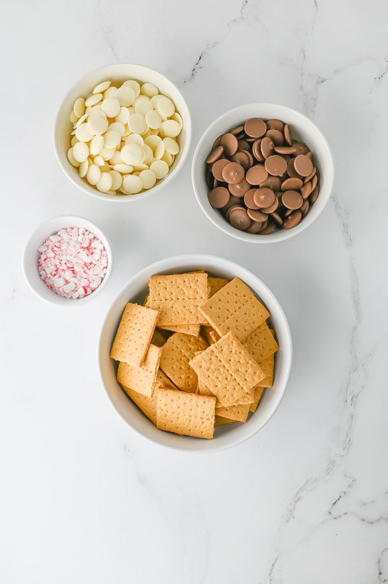 Ingredients for peppermint crunch grahama crackers in small bowls on kitchen counter.
