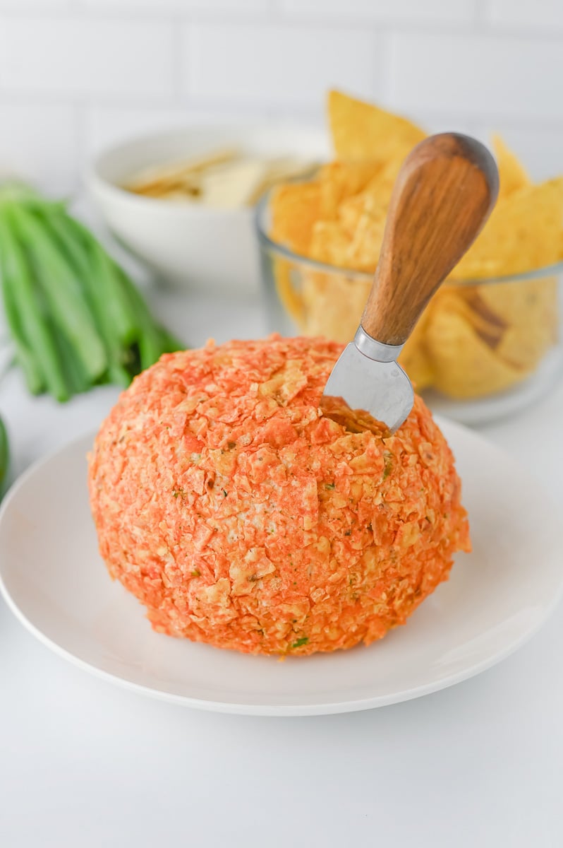 Cheese bal is rolled in crushed Doritos and placed on plate.
