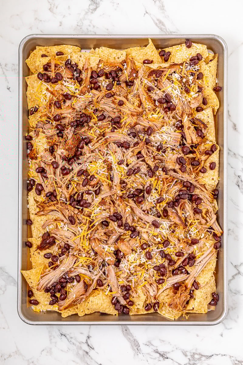 Pulled pork, another layer of shredded cheese and black beans is added to the nachos.
