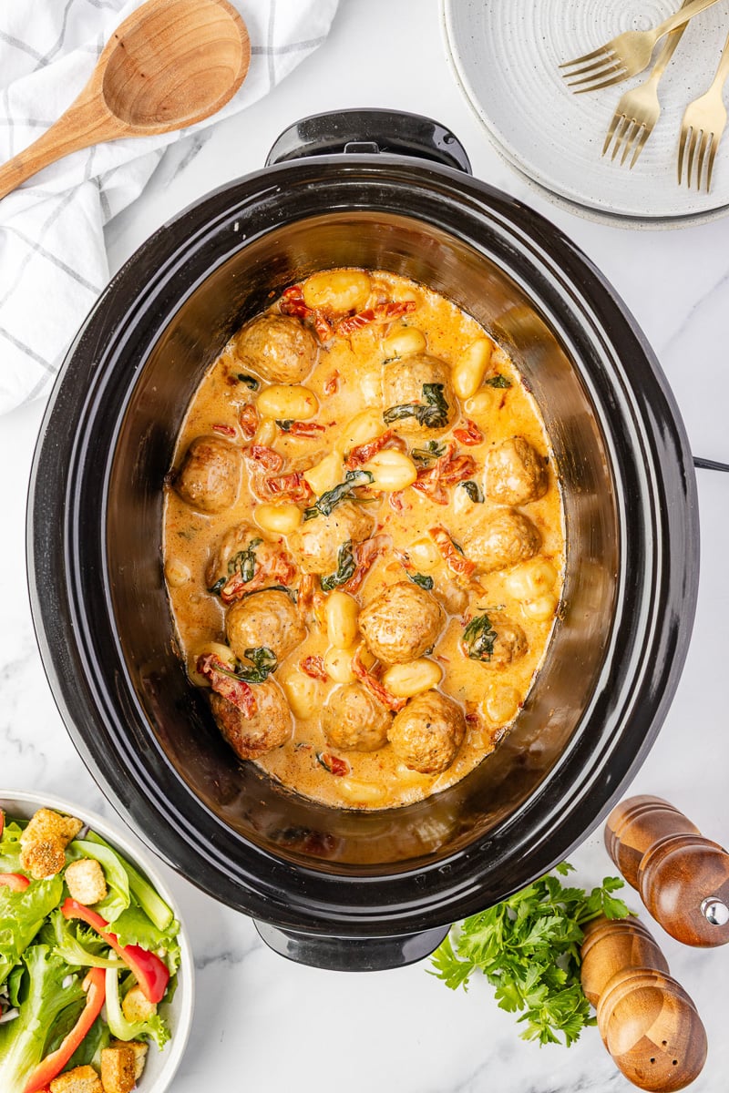 Finished dish of tuscan chicken meatballs overhead view in crockpot.