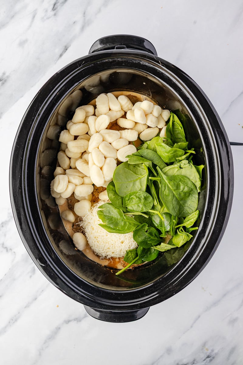 Spinach and gnocchi are added to the slow cooker.