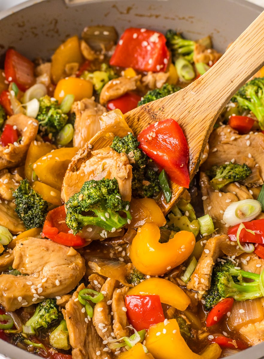 Stir fried chicken in skillet, scooped up on spoon.