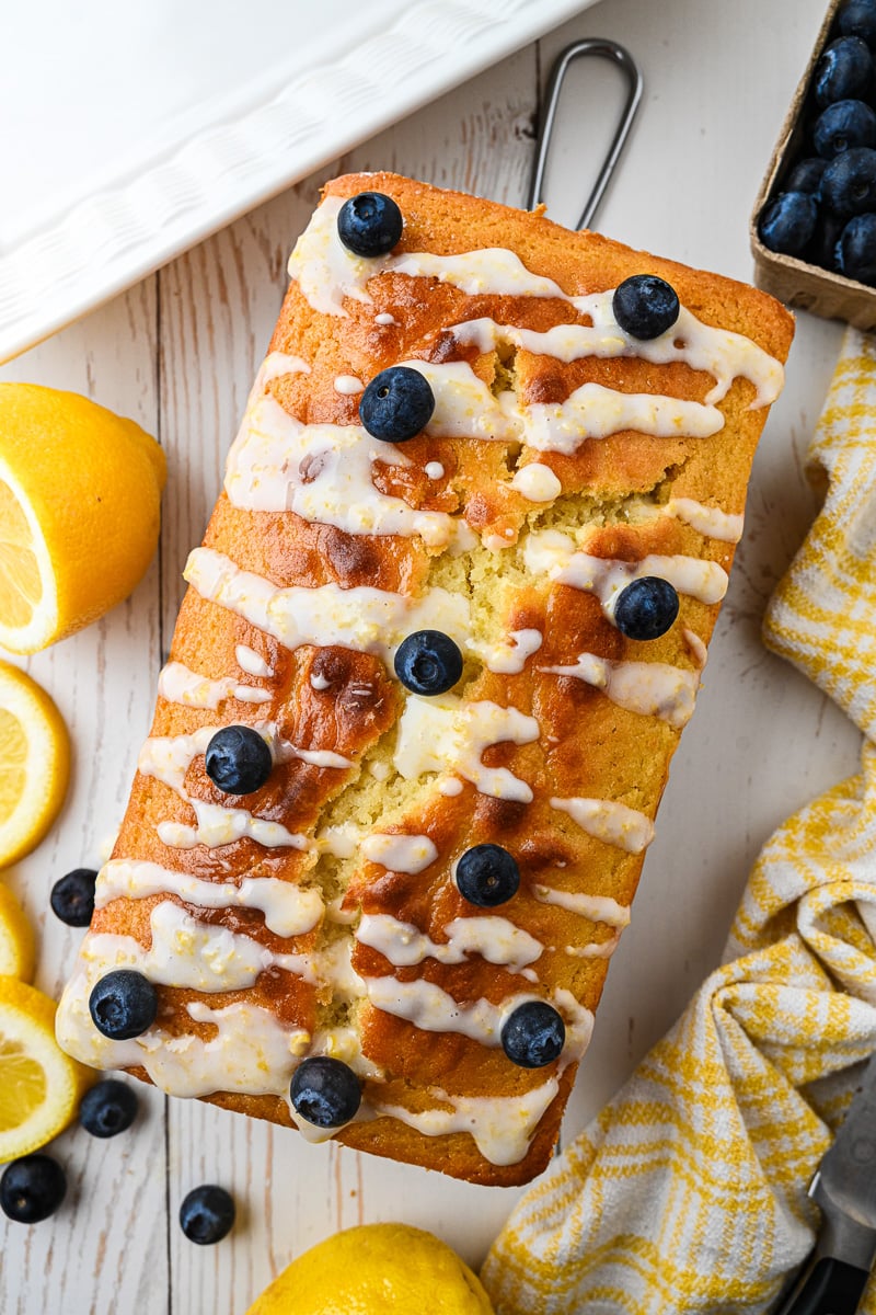 Glaze is drizzled on top of blueberry lemon loaf.