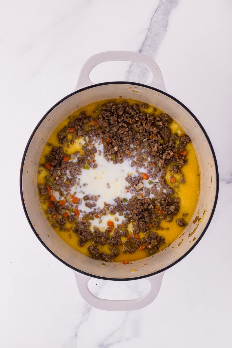 Milk and white wine are added to the cooking dish.