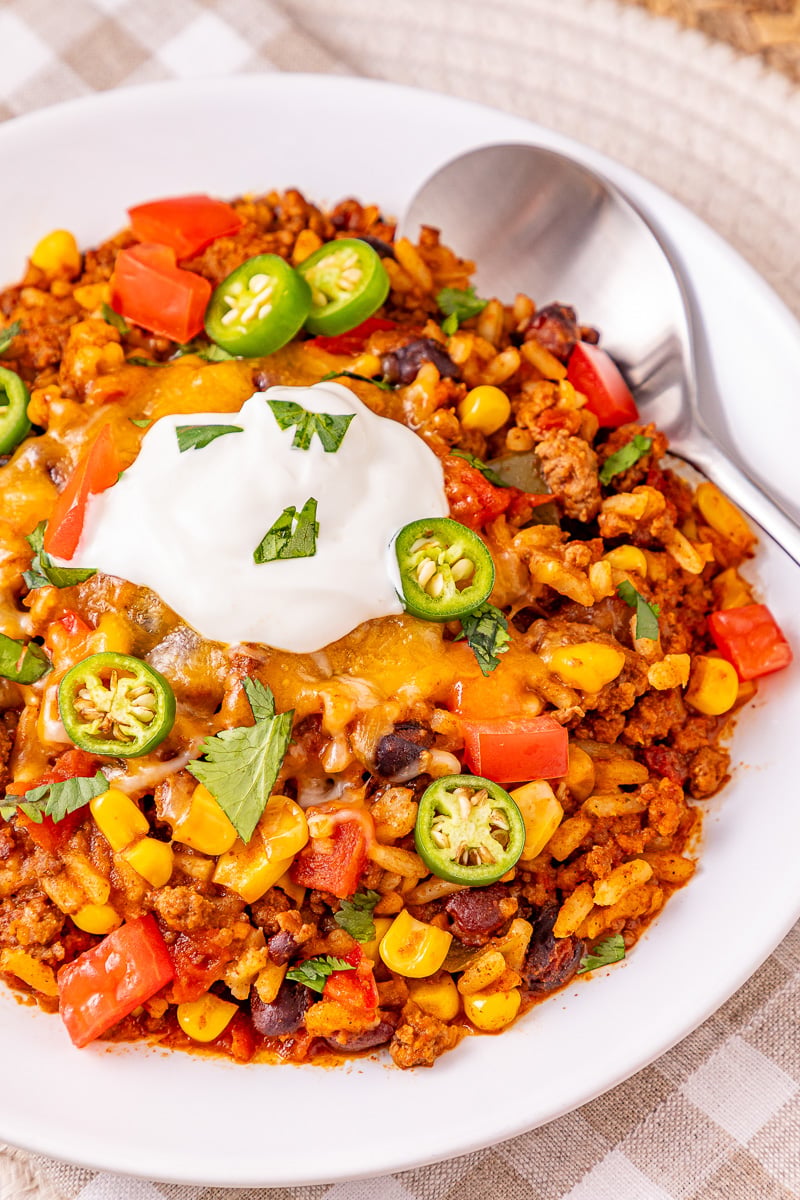 Mexican beef and rice casserole is served on a plate with sour cream and avocados.