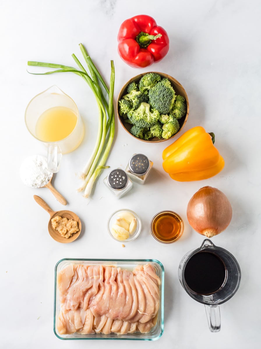 Ingredients for chicken stir fry in small bowls on counter.
