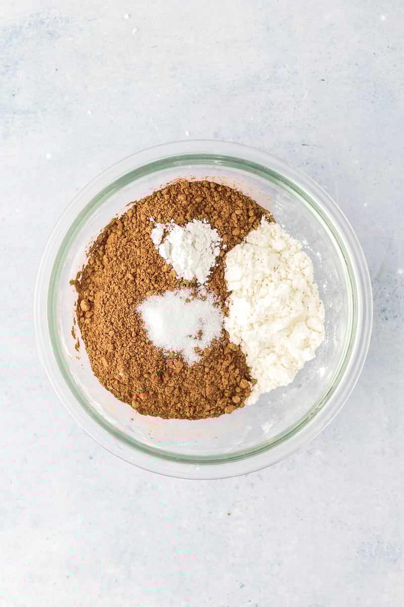 Cocoa powder for brownie layer in mixing bowl with other dry ingredients.