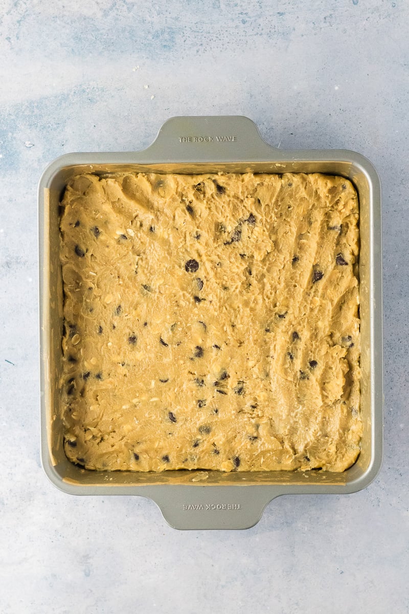 Chocolate chip cookie dough is pressed into the bottom of baking dish.