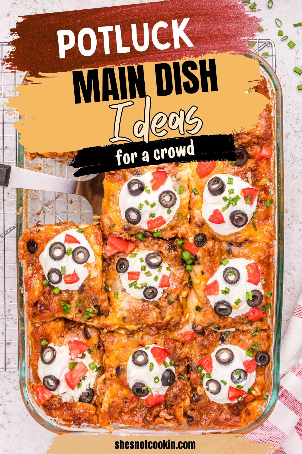 Mexican lasagan overhead view in baking dish topped with sour cream and black olives.