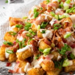 Loaded tater tots on a plate.