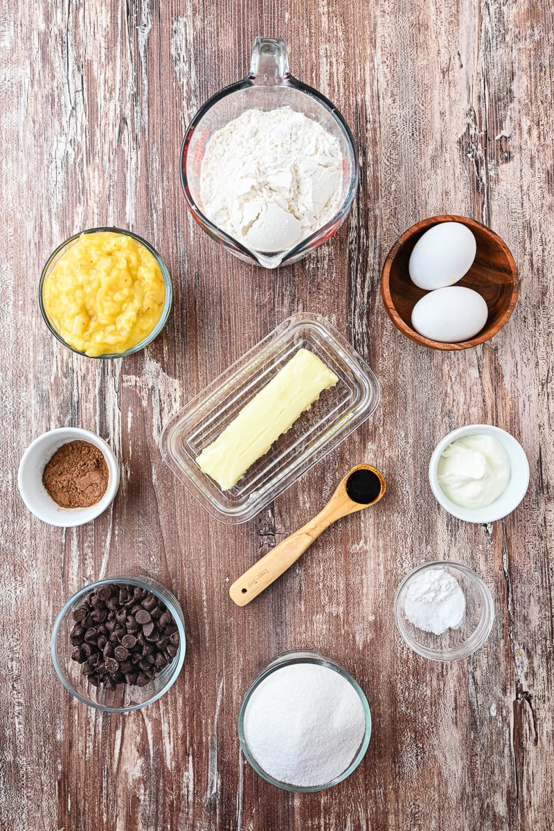 Ingredients for chocolate banana loaf cake in small bowls on kitchen counter.