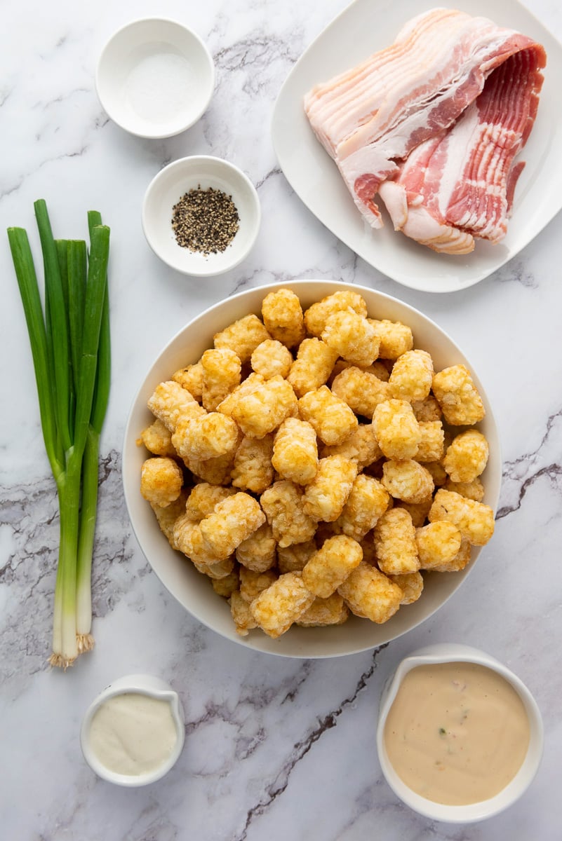 Ingredients for loaded tater tots in small bowls on kitchen counter.
