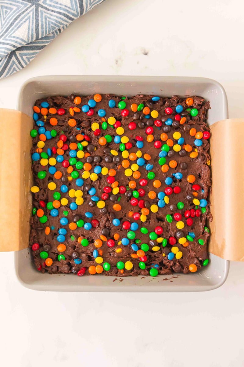Remaining M&M's are sprinkled on top of the batter spread out in cakke pan.