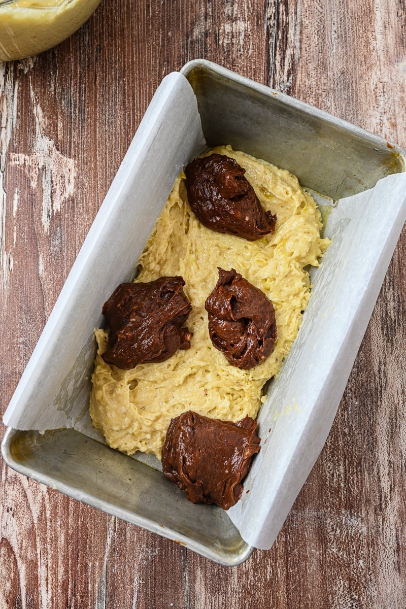 Half of the batter is placed in loaf plan and then the chocolate batter is dropped on top in sections.