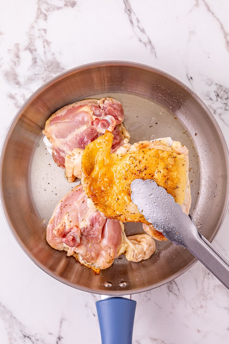 Chicken thighs are searced in skillet.