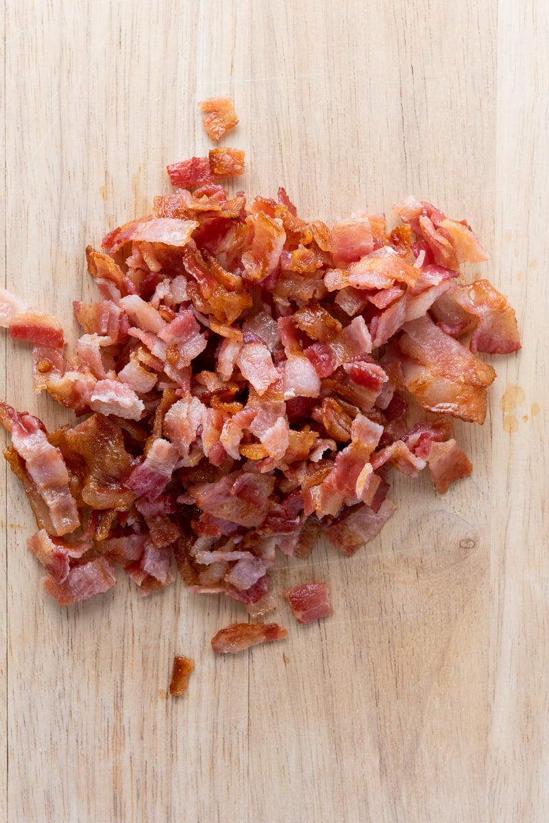 Chopped bacon on wooden cutting board.