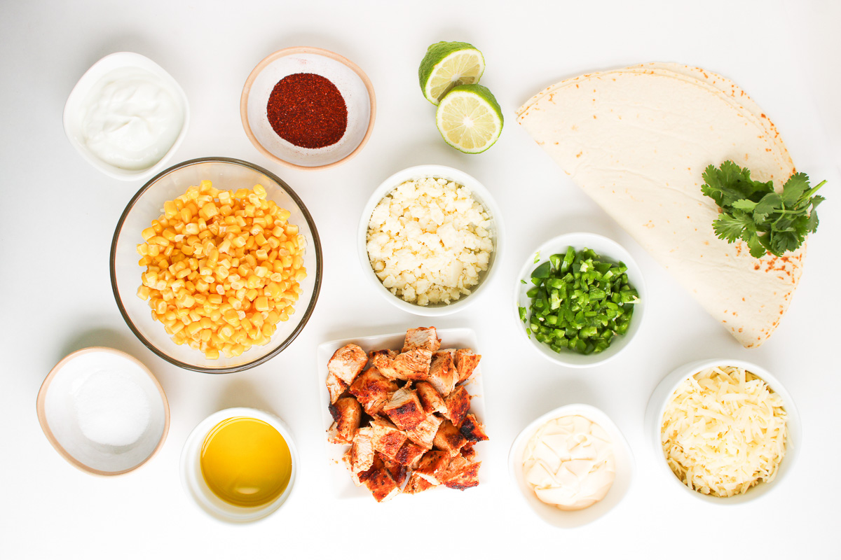 Ingredients for street corn quesadillas laid out in small bowls on the counter.
