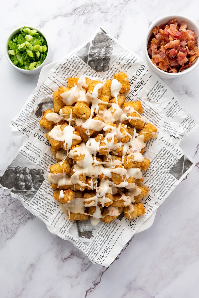 Queso is drizzled on top of cooked tater tots.
