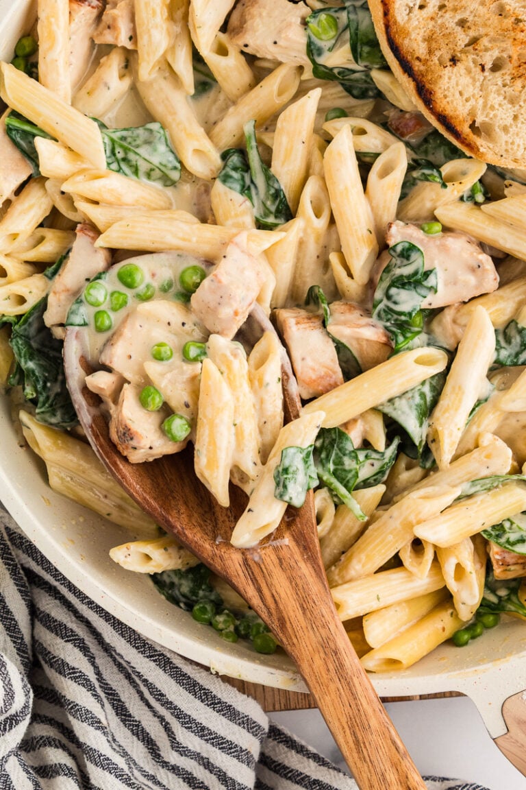 Scoop of Boursin pasta with chicken held over skillet.