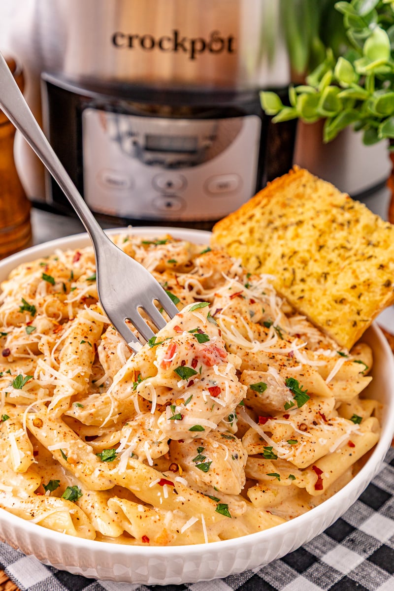 Crockpot cajun chicken pasta served in a bowl with garlic bread on the side.