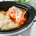 Crockpot ravioli lasagna in slow cooker scooped up with a spoon.