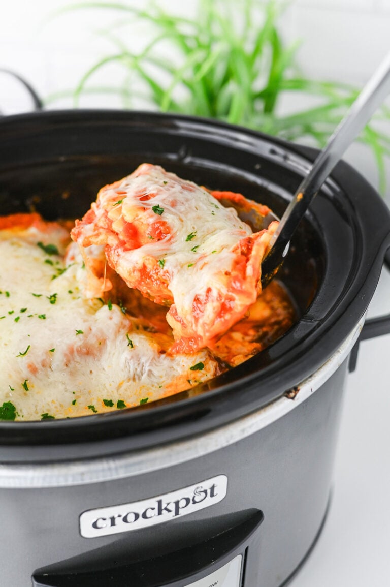 Crockpot ravioli lasagna in slow cooker scooped up with a spoon.