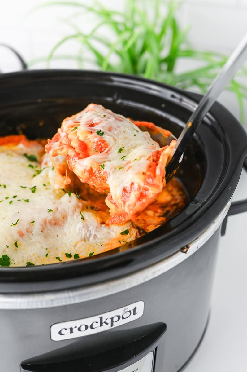 Crockpot ravioli lasagna in slow cooker scooped up with a spoon.