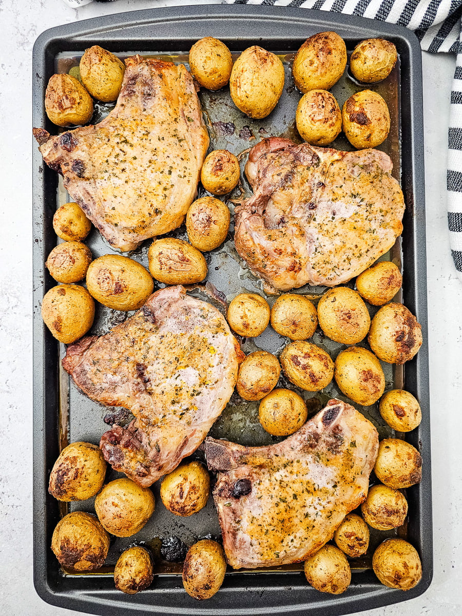 Sheet pan pork chops and potatoes on baking sheet, ready to be served.
