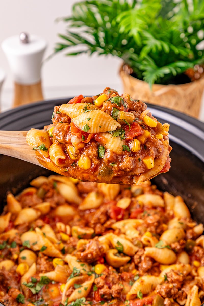 Crockpot taco pasta scooped up on serving spoon.