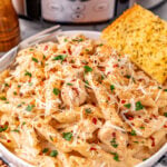 Crockpot chicken cajun pasta in white bowl with garlic bread on the side.