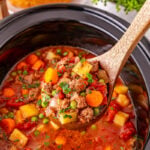 Poor man's stew scooped up and held over slow cooker.