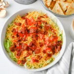 BLT dip in bowl ready to be served with crackers and chips on the side.