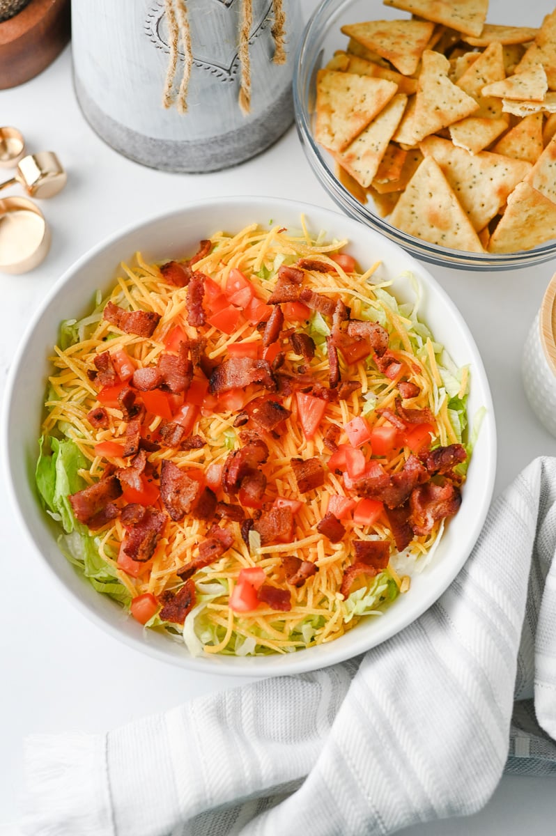 BLT dip in bowl ready to be served with crackers and chips on the side.