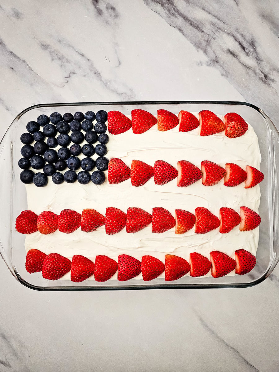 Strawberries and blueberries are placed on top of cake.