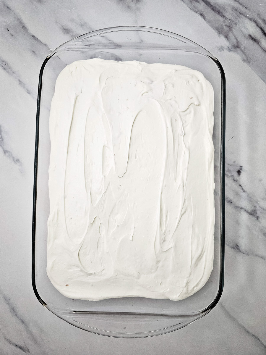 Frosting mixture is spread on top of baked cake.