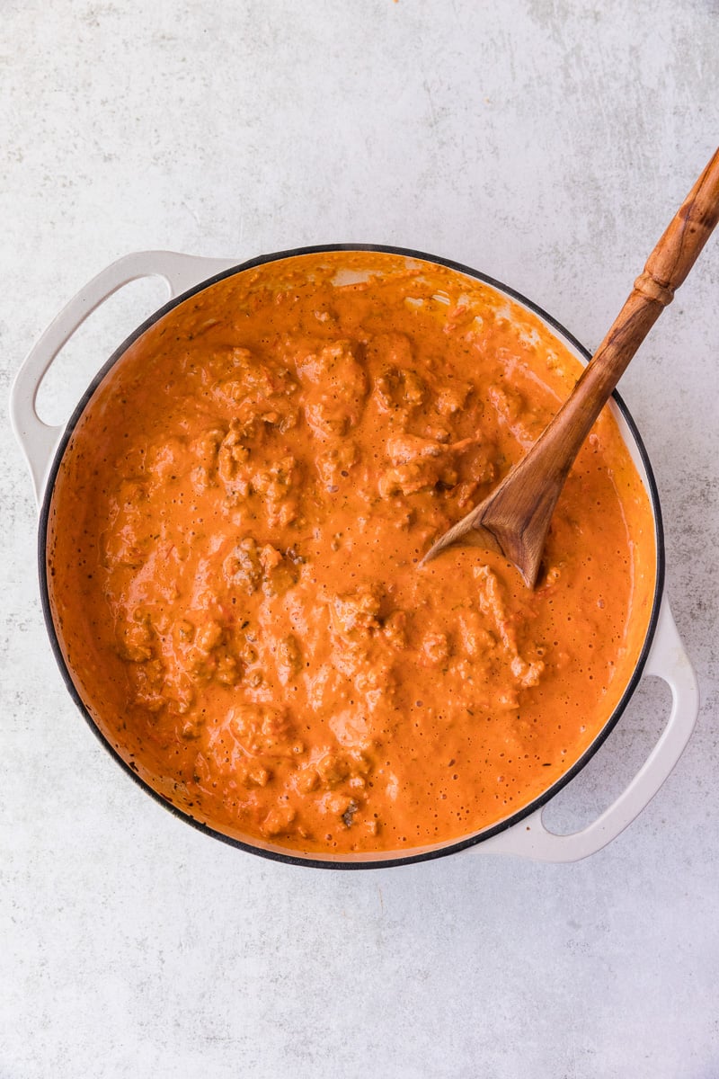 Tomato sauce is added to the cooked sausage in skillet.