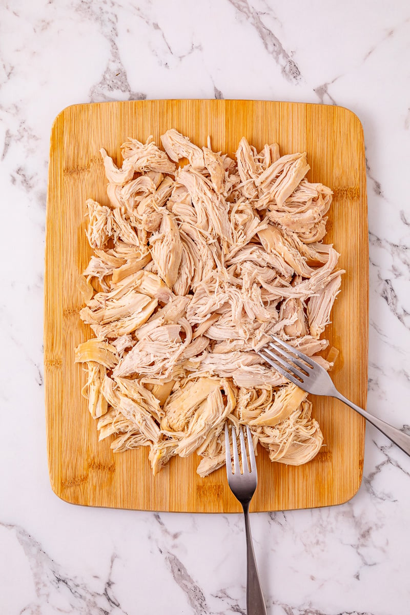 Shredded chicken on cutting board.