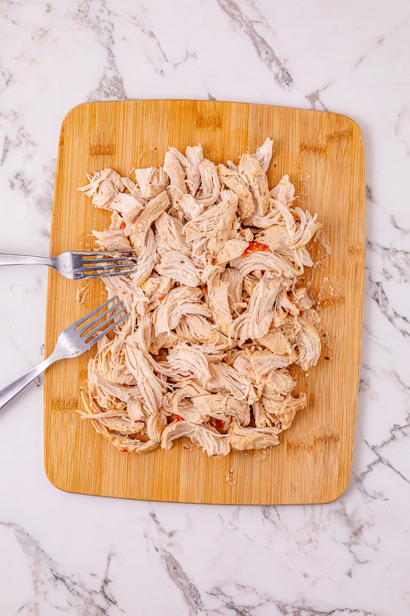 Chicken is removed and placed on cutting board and shredded before returning to the crockpot.