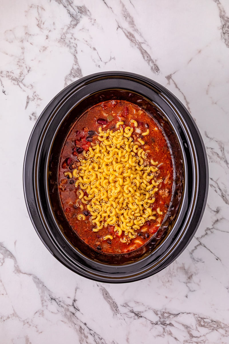 Uncooked macaroni is added to the crockpot.