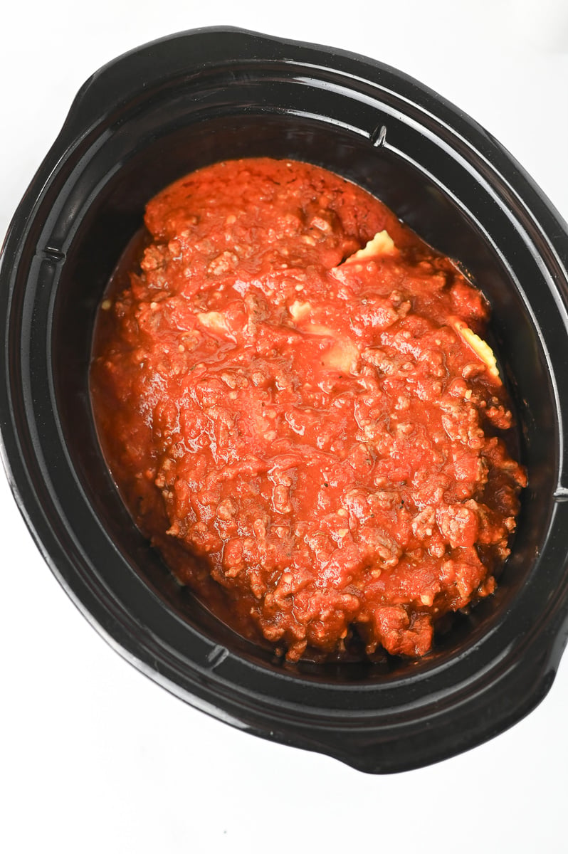 Remaining ravioli and a final layer of sauce are added to the crockpot.