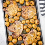 Sheet pan pork chops and pogtatoes on baking sheet, ready be served.