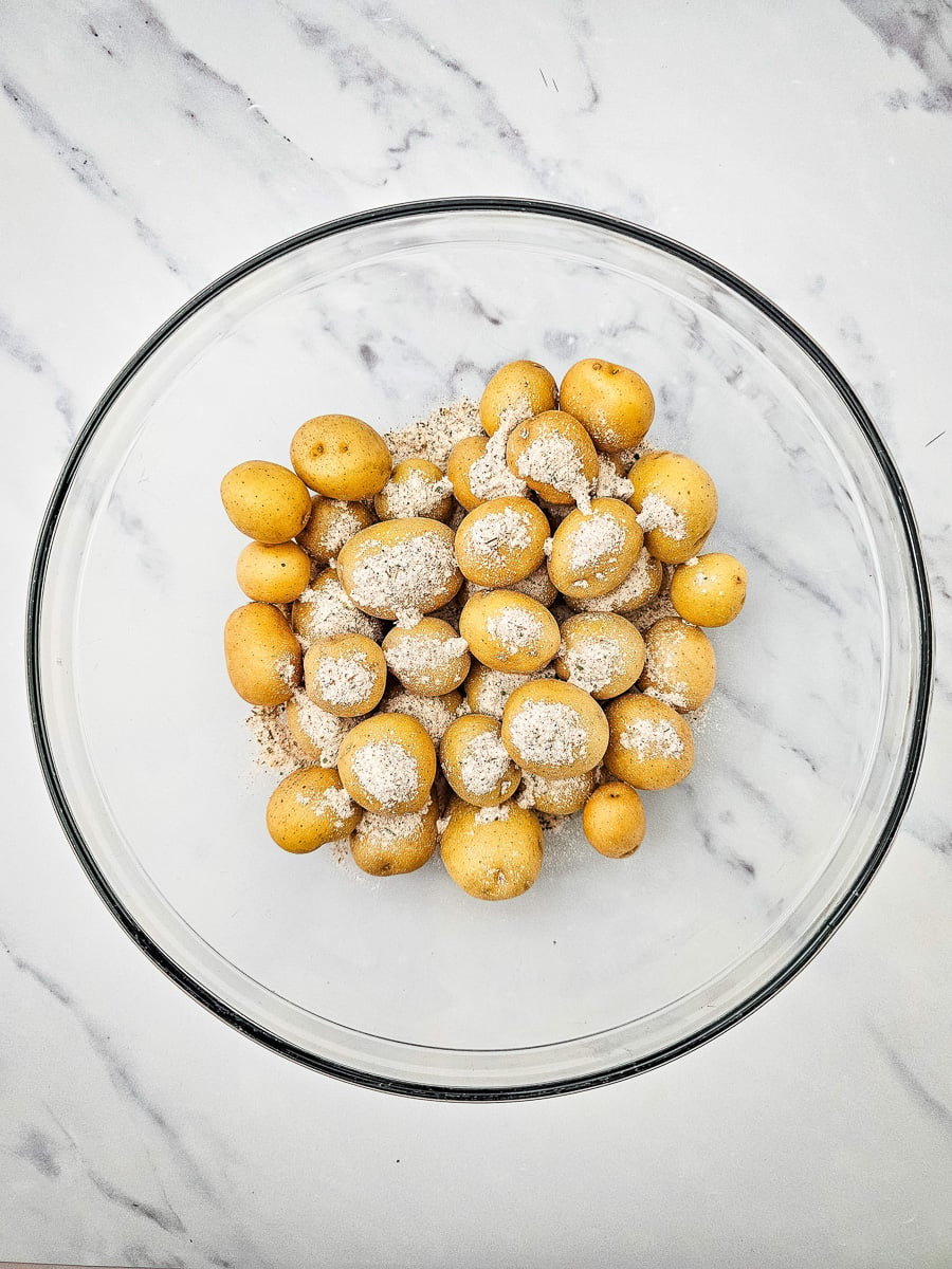 Seasonings are poured over potatoes in small bowl.