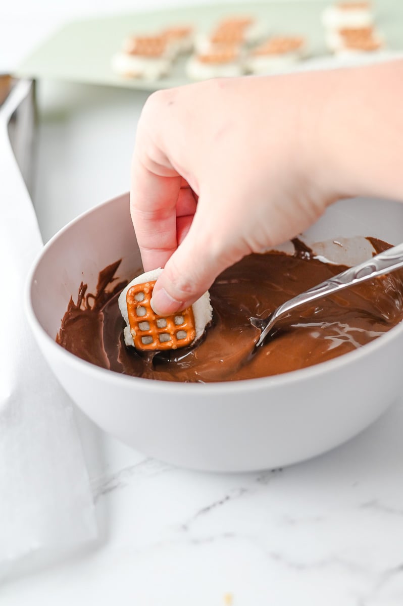 Pretzel is dipped into melted chocolate.