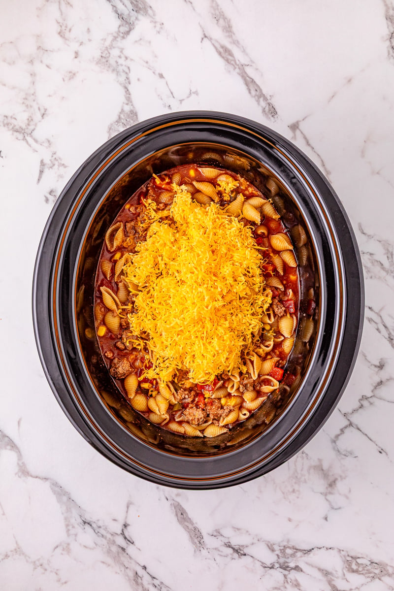 Shredded cheddar cheese is added to the slow cooker.
