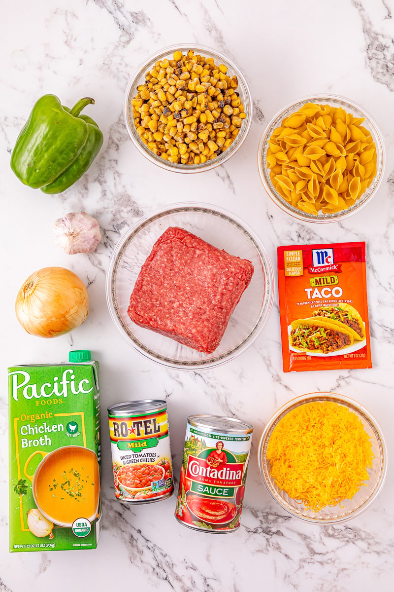 Ingredients for slow cooker taco pasta in bowls on kitchen counter.