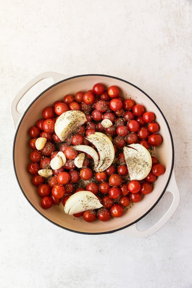 Cherry tomatoes, onions and garlic with seasonings in oven-proof skillet.